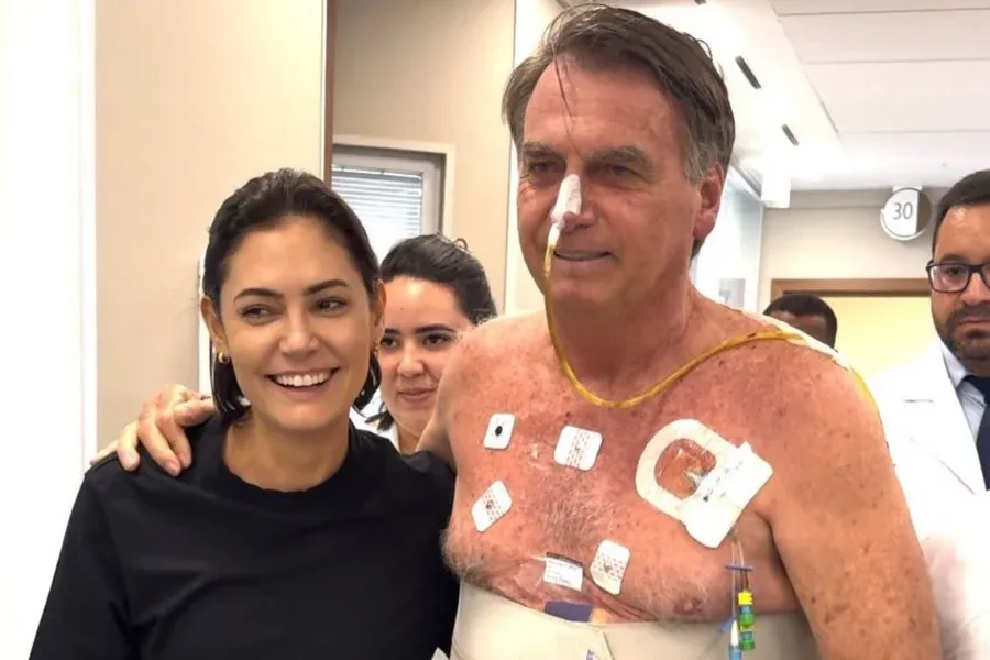 Michelle Bolsonaro e Jair Bolsonaro em momento de oração e cuidado no hospital, com a legenda "Seguirei cuidando".
