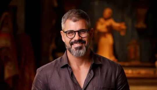 O ator Juliano Cazarré em primeiro plano durante entrevista reafirmando seus posicionamentos conservadores e religiosos.