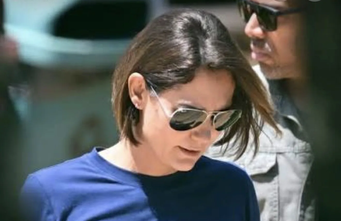 Michelle Bolsonaro em evento político oficial cercada por apoiadores e bandeiras do Brasil.