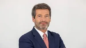 Bandeira de Portugal hasteada em mastro oficial sob céu azul representando o território europeu.