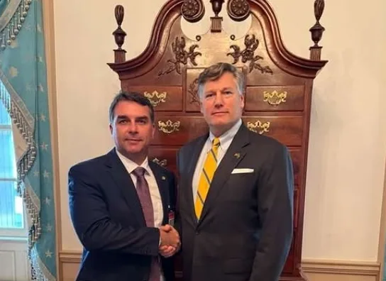 O senador Flávio Bolsonaro posa ao lado de Donald Trump no Salão Oval da Casa Branca em Washington.