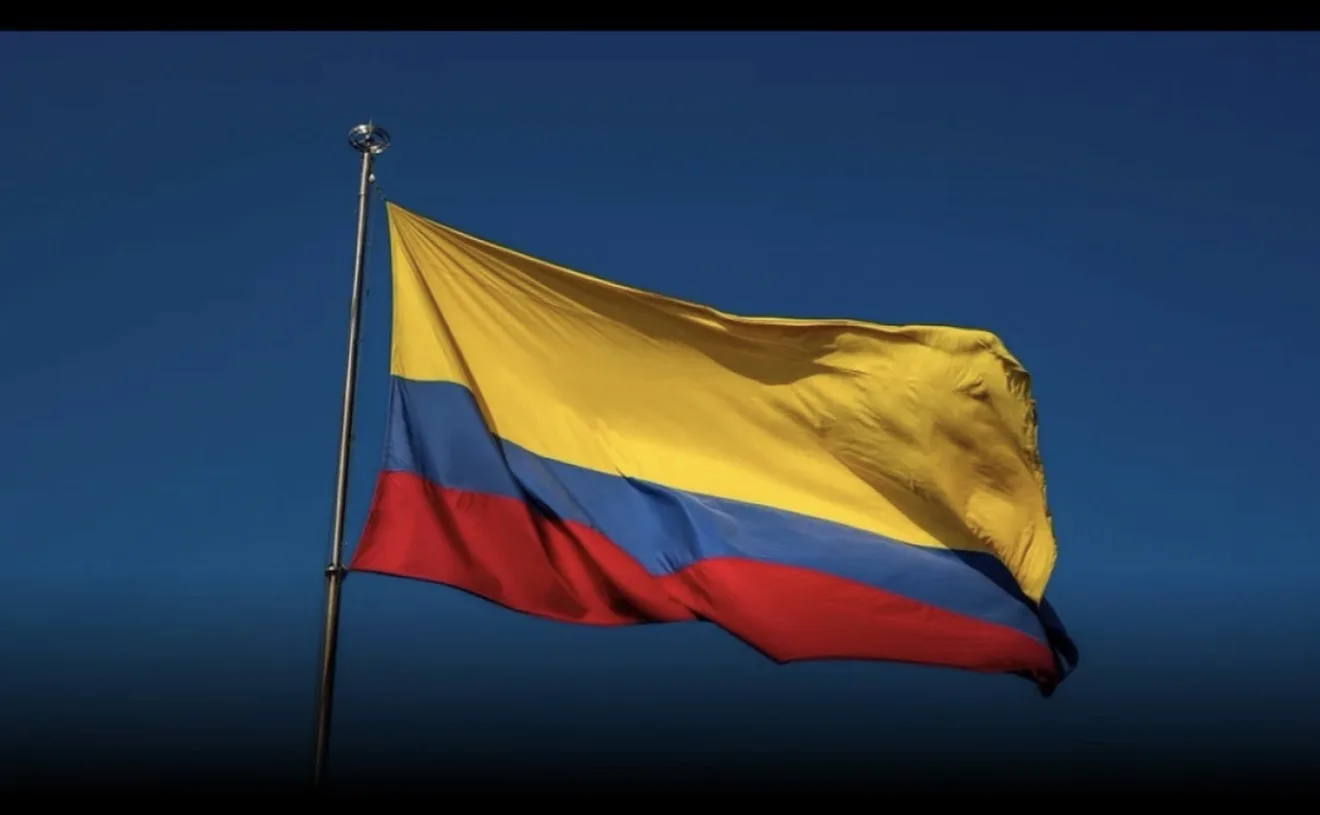 Bandeira da Colômbia hasteada contra o céu azul.