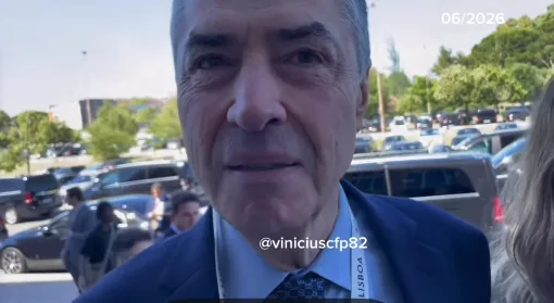 Comunicador Didi Red Pill segurando microfone e questionando autoridade brasileira na entrada de evento em Portugal.