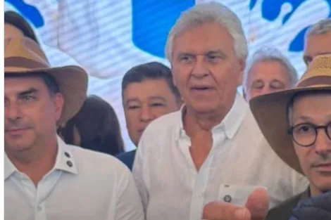O senador Flávio Bolsonaro e o governador Romeu Zema brindando com copos de leite durante evento político.