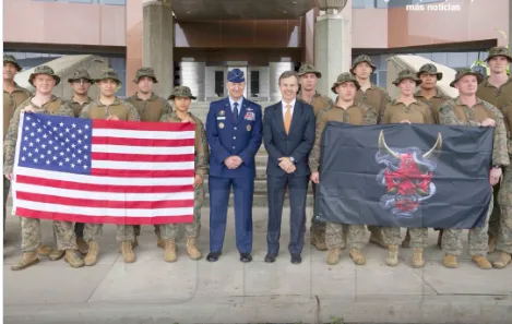General militar americano fardado discursando em púlpito oficial com bandeira dos Estados Unidos ao fundo.