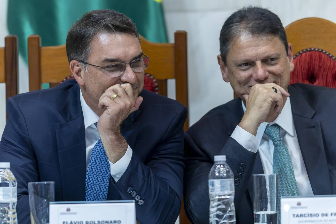 Flávio Bolsonaro e Tarcísio de Freitas sentados lado a lado durante encontro político