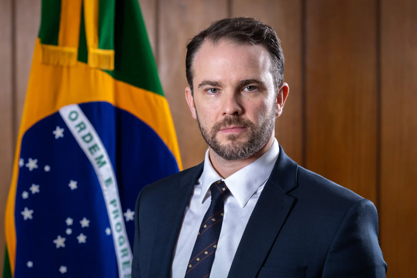 Dario Durigan, ministro da Fazenda, diante da bandeira brasileira