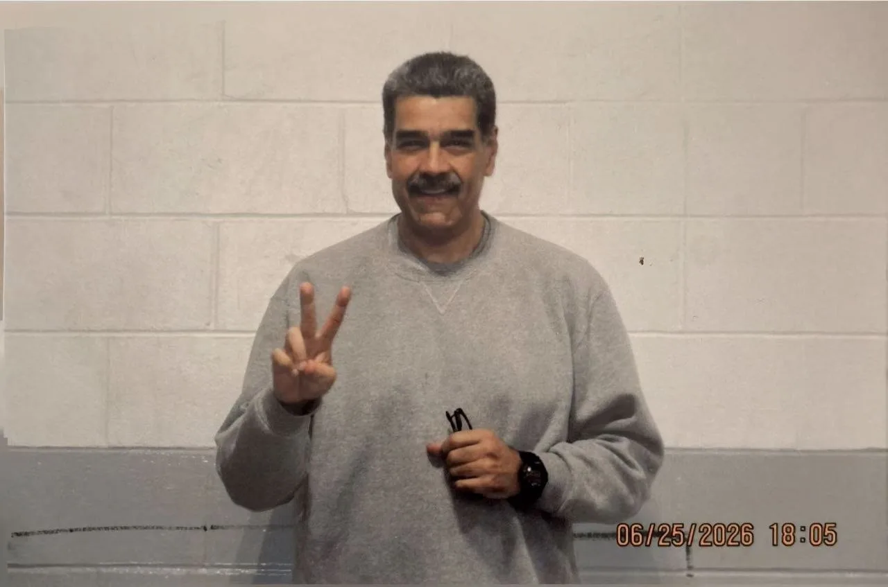 Nicolás Maduro de moletom cinza na prisão dos Estados Unidos, fazendo gesto de V