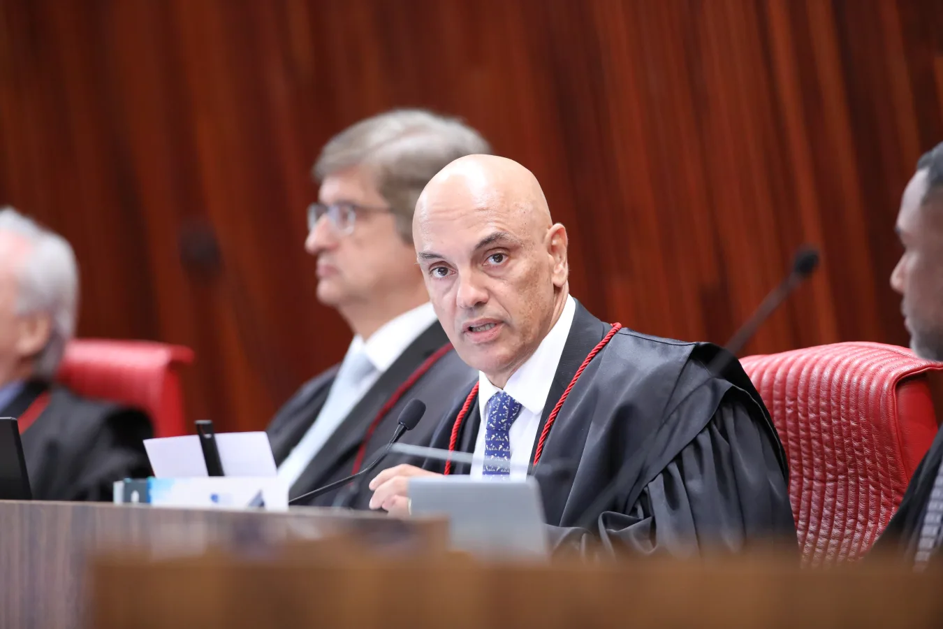 Alexandre de Moraes, de toga, em sessão do TSE na cadeira vermelha