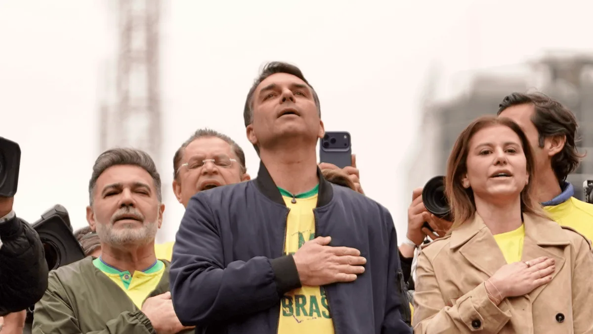 Flávio Bolsonaro de jaqueta azul e camisa amarela BRASIL, mão no peito durante o hino no ato de 7 de Setembro na avenida Paulista
