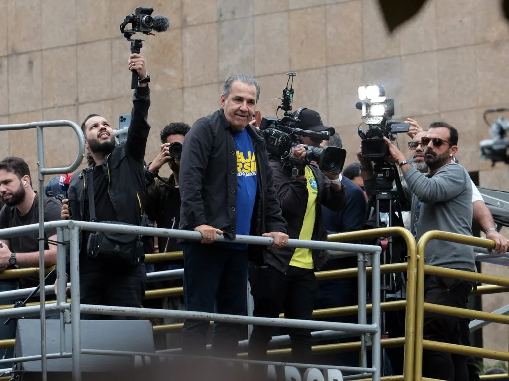 Pastor Silas Malafaia de camiseta azul com a palavra Brasil, em trio elétrico na Avenida Paulista, cercado por cinegrafistas