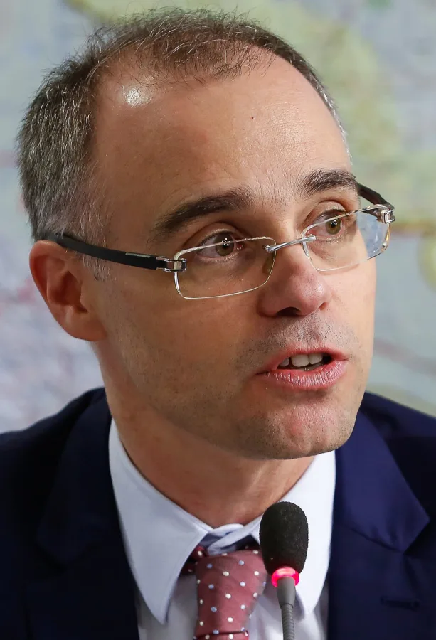 André Mendonça de óculos, terno escuro e gravata bordô com poá, falando ao microfone