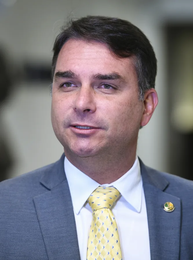 Senador Flávio Bolsonaro de terno escuro e gravata azul durante entrevista no Senado