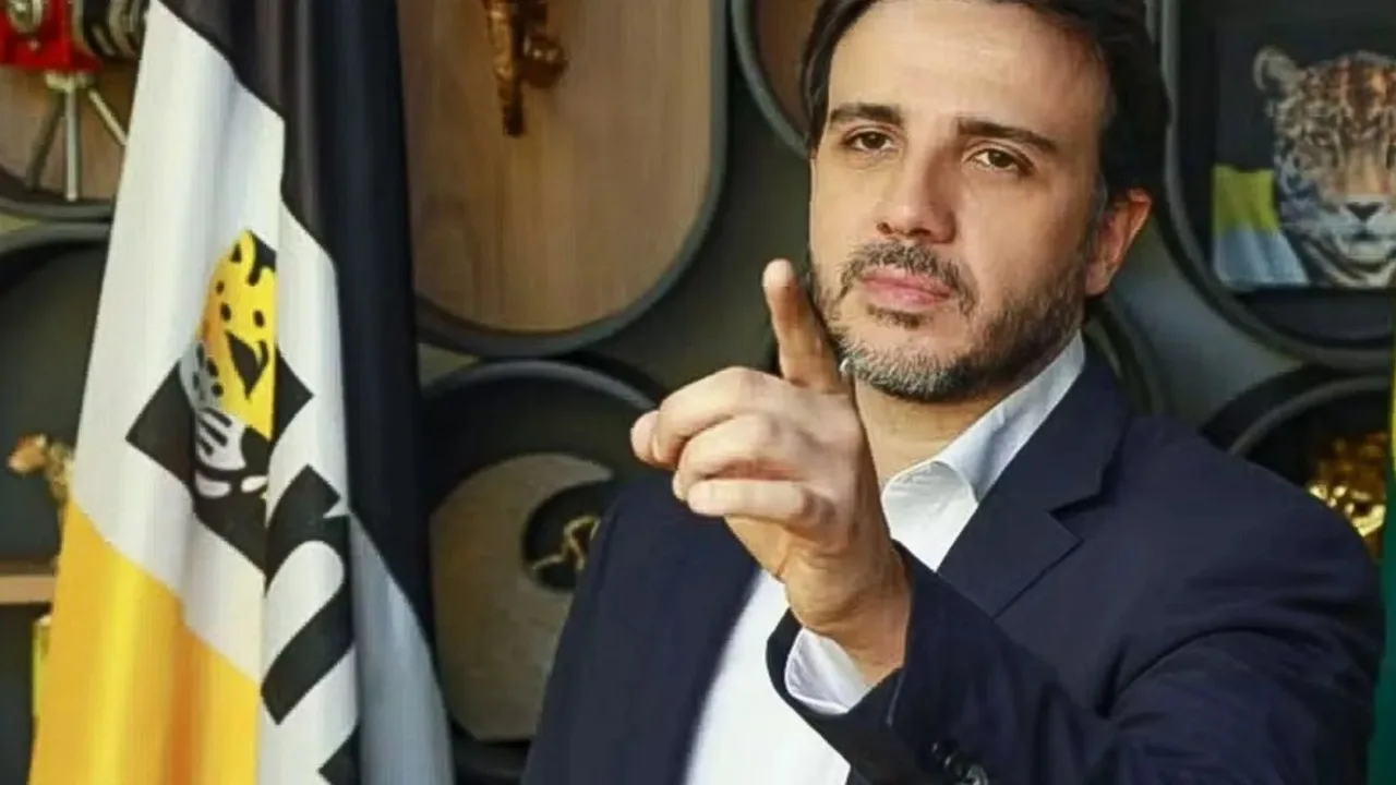 Renan Santos, do MBL/Missão, gesticulando em entrevista com bandeira do movimento ao fundo