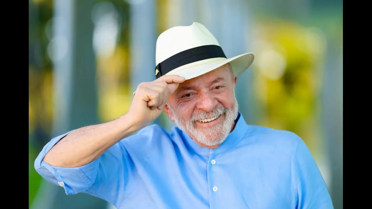 O presidente Lula, de chapéu panamá e camisa azul, toca a aba do chapéu