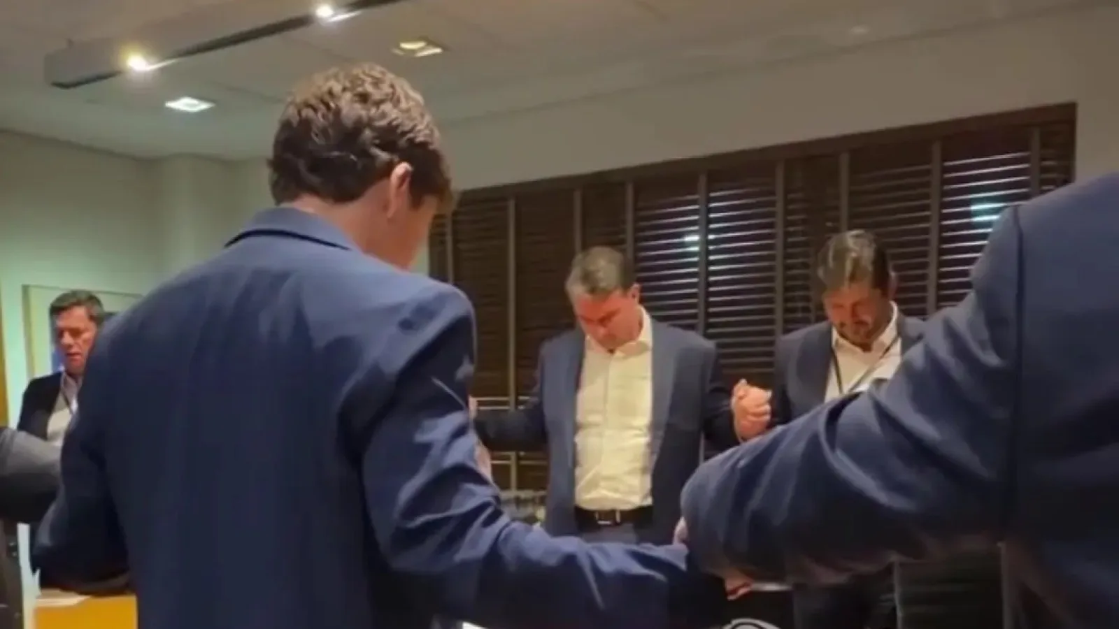 Flávio Bolsonaro de mãos dadas com aliados durante oração antes do debate da Band.